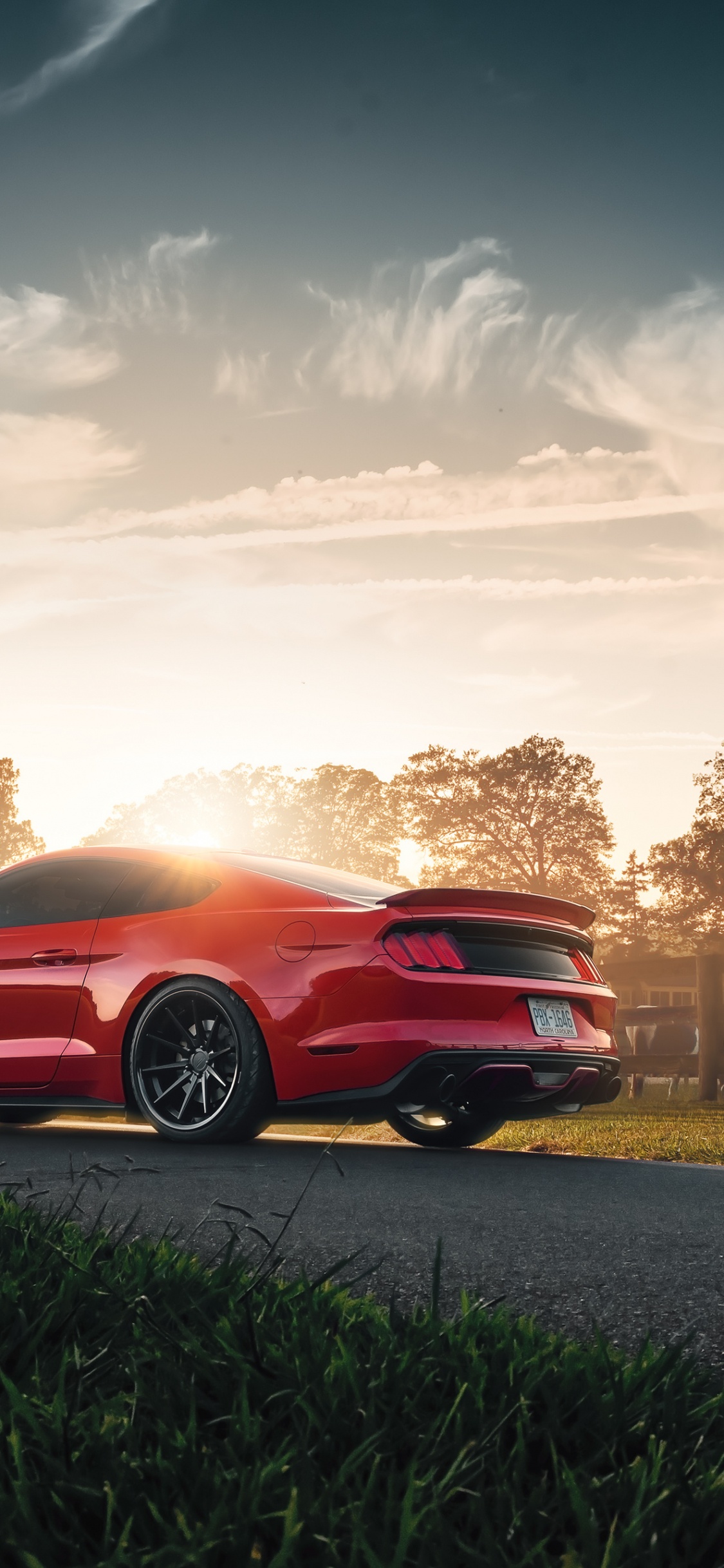 Roter Chevrolet Camaro Unterwegs Bei Sonnenuntergang During. Wallpaper in 1125x2436 Resolution