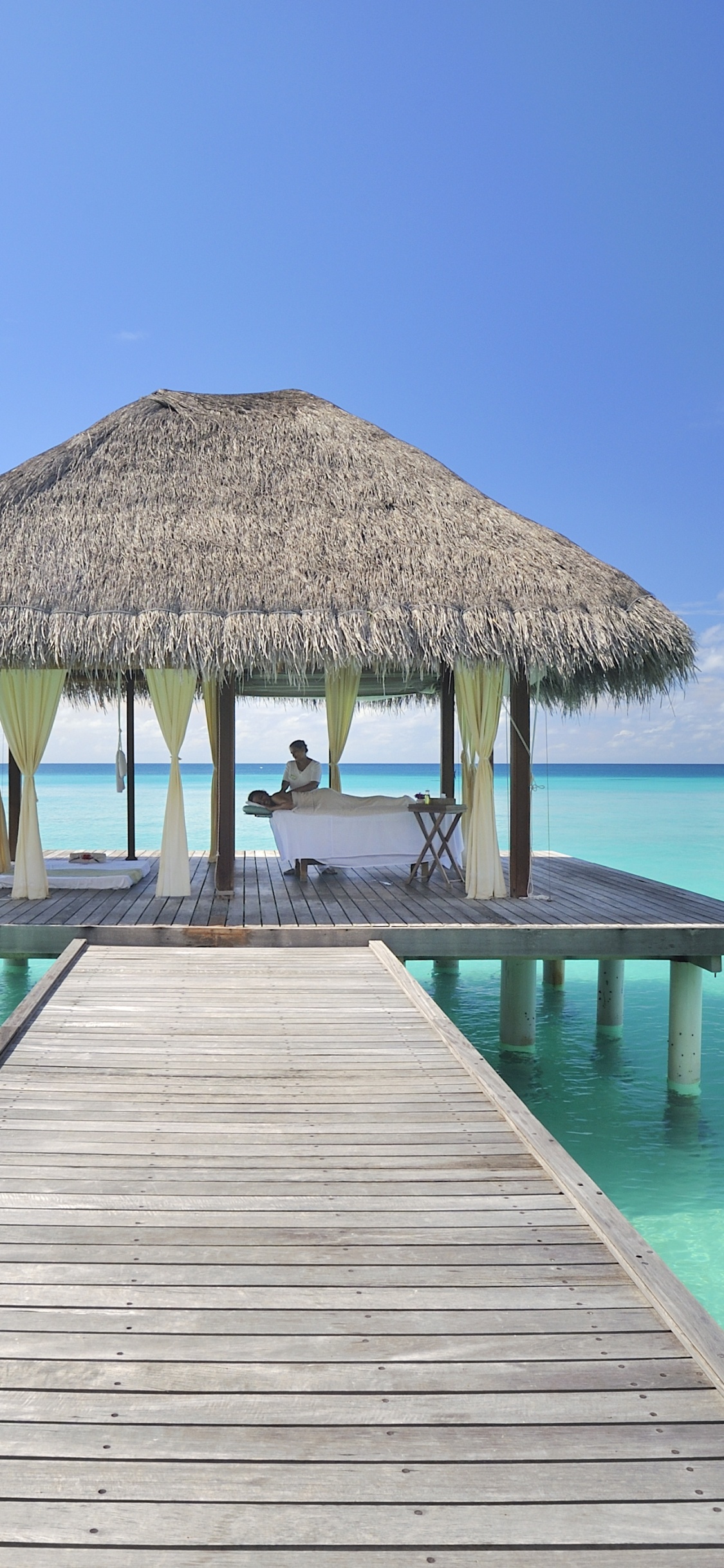 Brown Wooden Dock on Blue Sea Under Blue Sky During Daytime. Wallpaper in 1125x2436 Resolution