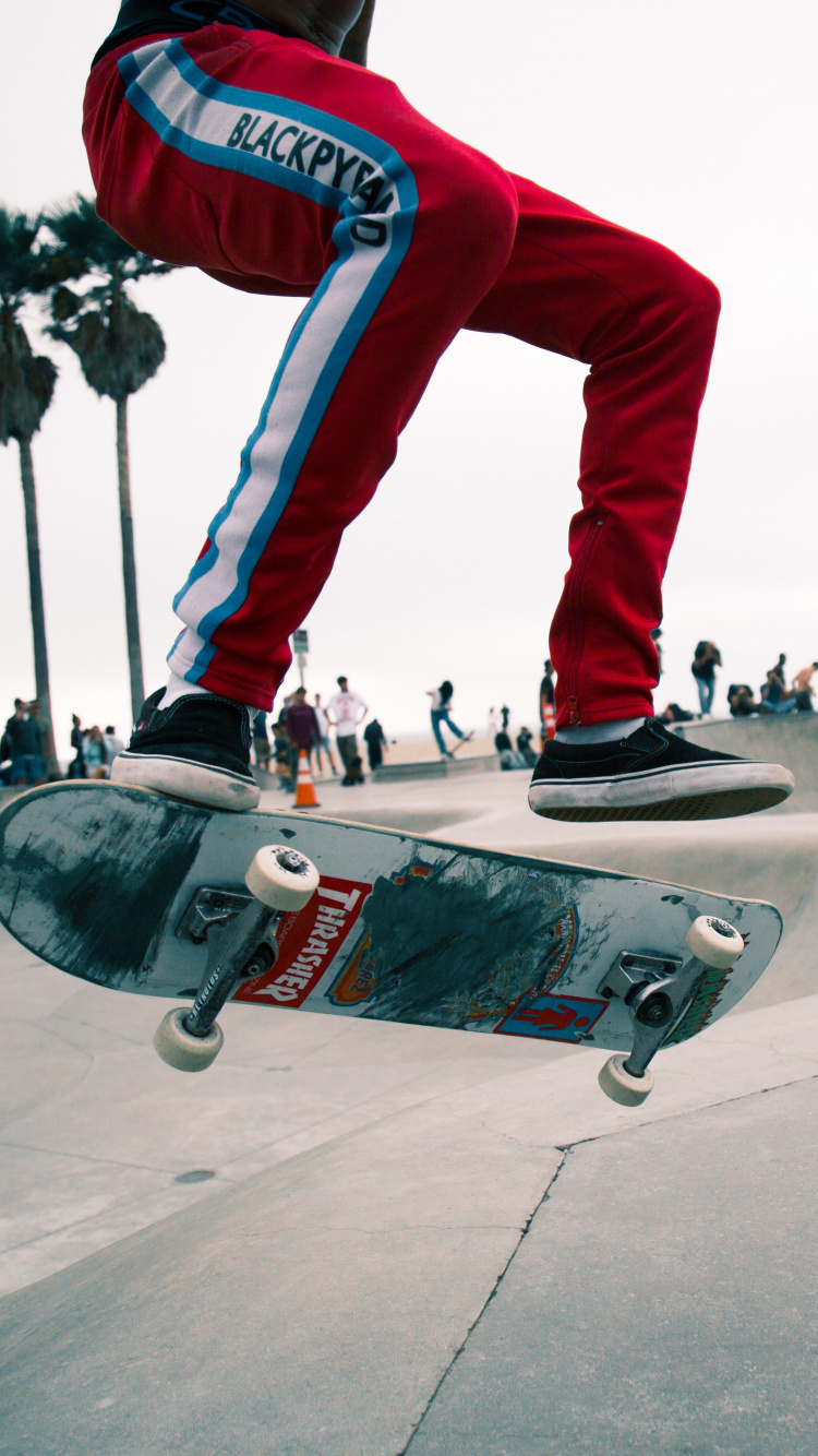 Mann in Roten Hosen Und Schwarz-weißen Turnschuhen, Die Skateboard Fahren. Wallpaper in 750x1334 Resolution