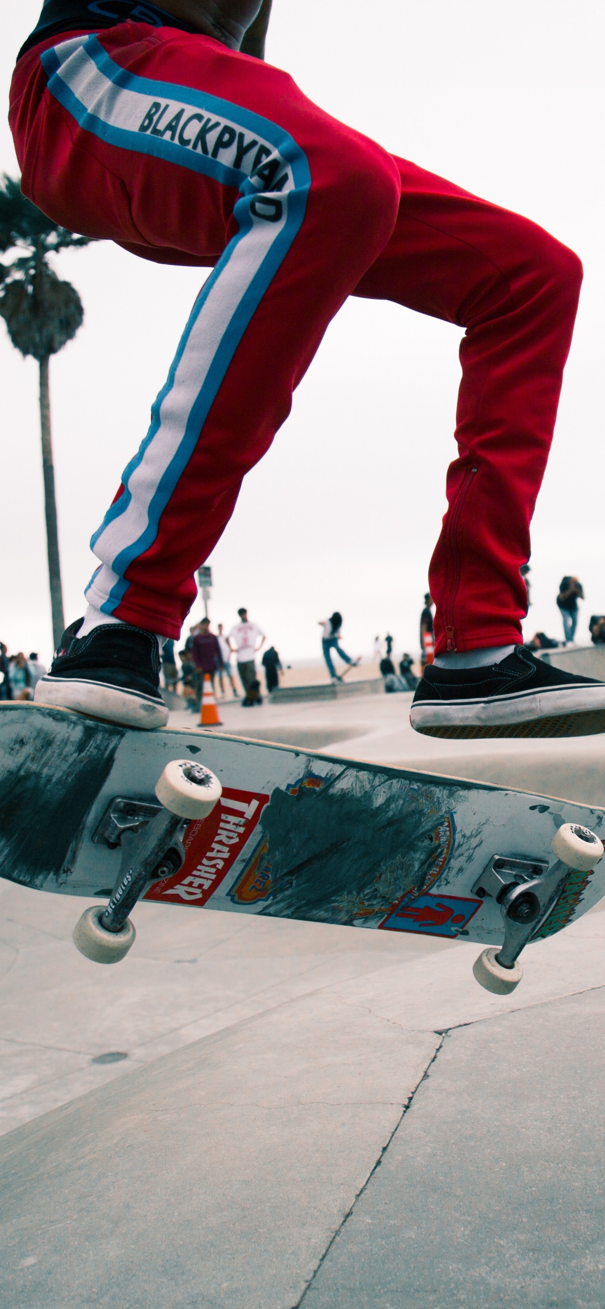 Man in Red Pants and Black and White Sneakers Riding Skateboard. Wallpaper in 1242x2688 Resolution