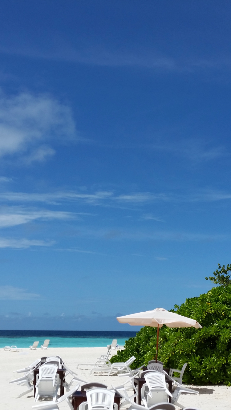 People Sitting on White Chairs Under Brown Beach Umbrella During Daytime. Wallpaper in 750x1334 Resolution