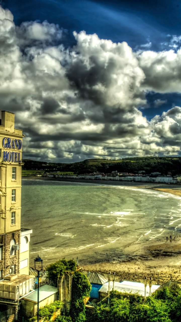 Bâtiment en Béton Brun Près D'un Plan D'eau Sous un Ciel Nuageux Pendant la Journée. Wallpaper in 720x1280 Resolution