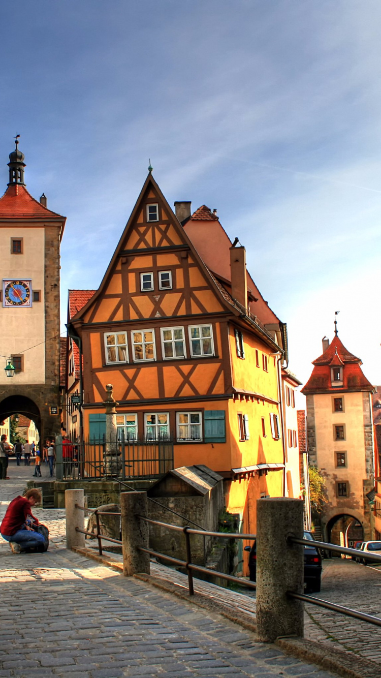 Leute, Die Tagsüber Auf Dem Bürgersteig in Der Nähe Eines Braunen Betongebäudes Gehen. Wallpaper in 750x1334 Resolution