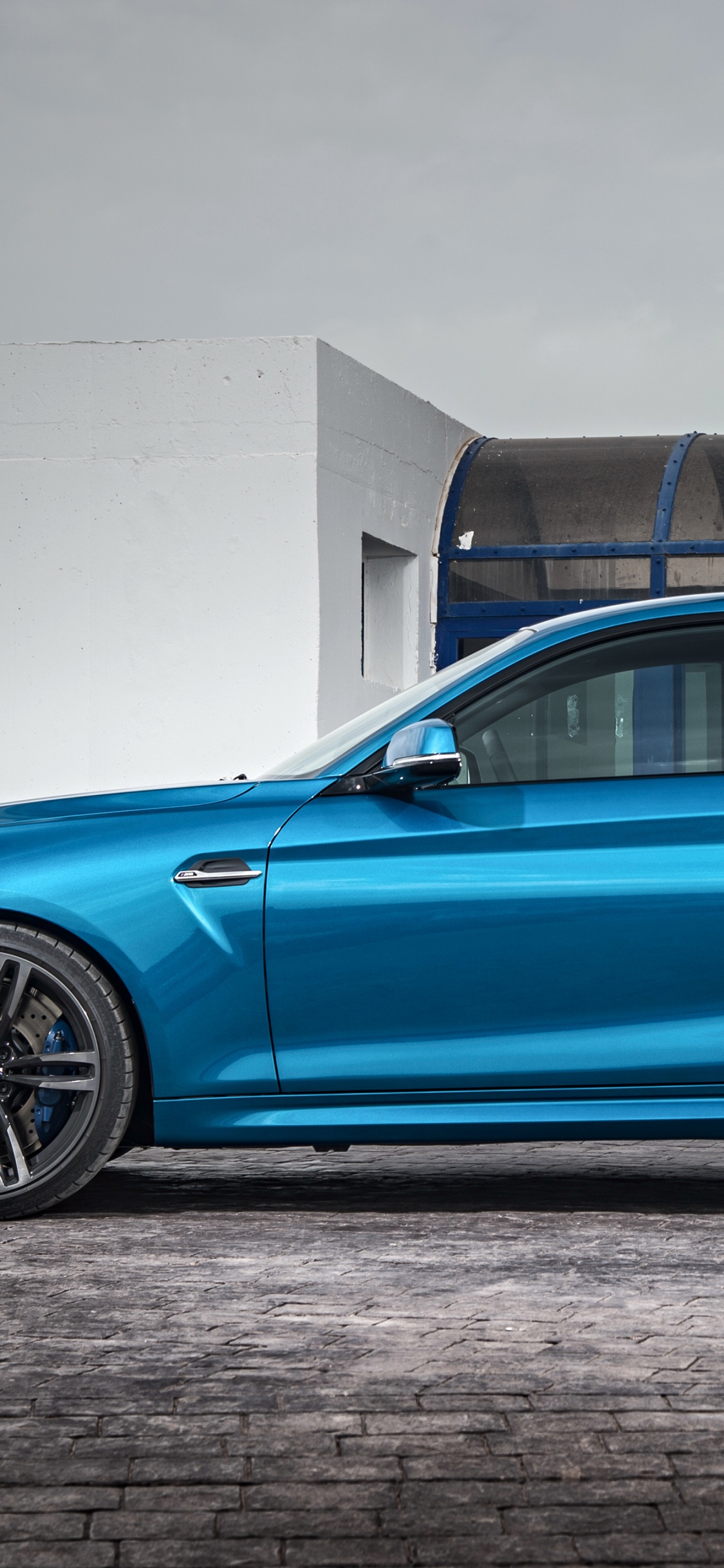 Blaue Limousine Neben Weißer Wand Geparkt. Wallpaper in 1125x2436 Resolution