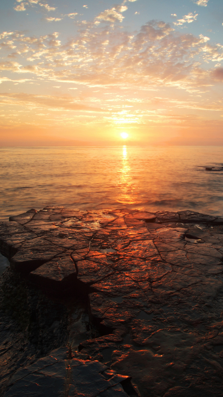 Felsiges Ufer Bei Sonnenuntergang Unter Blauem Himmel. Wallpaper in 750x1334 Resolution