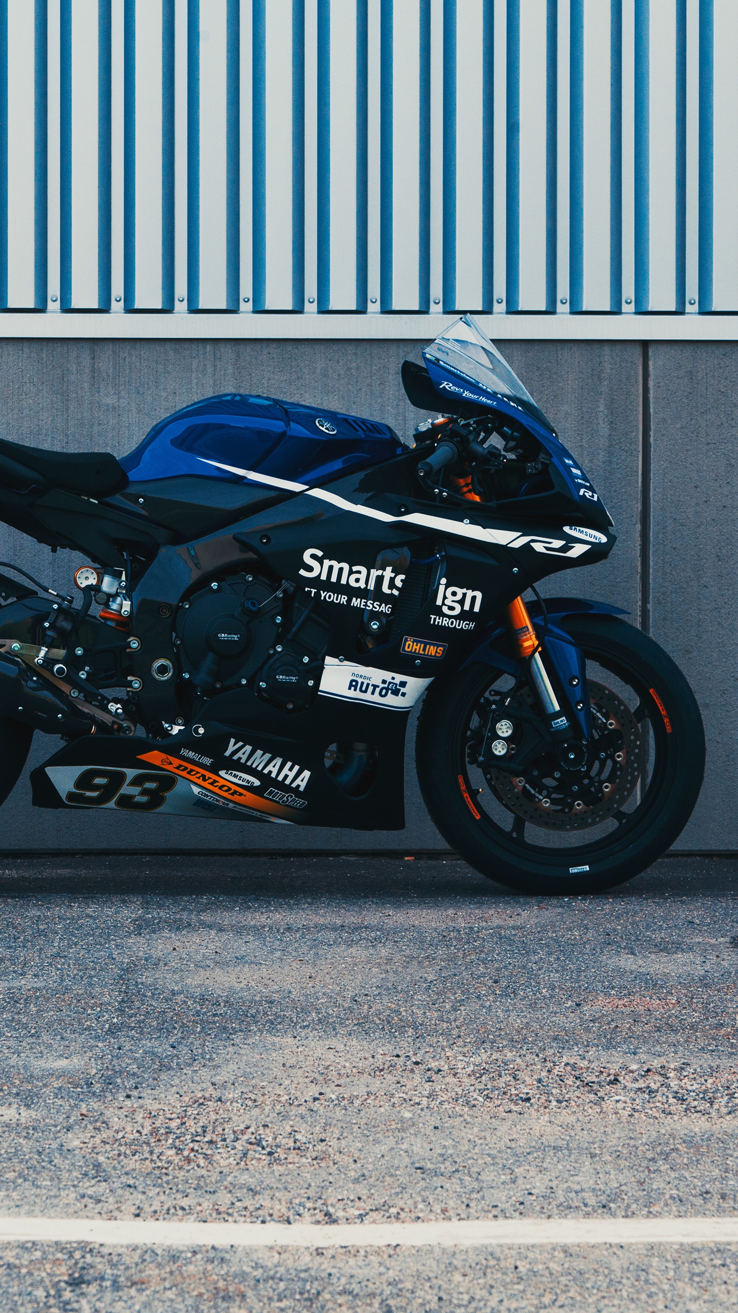 Black and Red Sports Bike Parked Beside Gray Roll up Door. Wallpaper in 1440x2560 Resolution