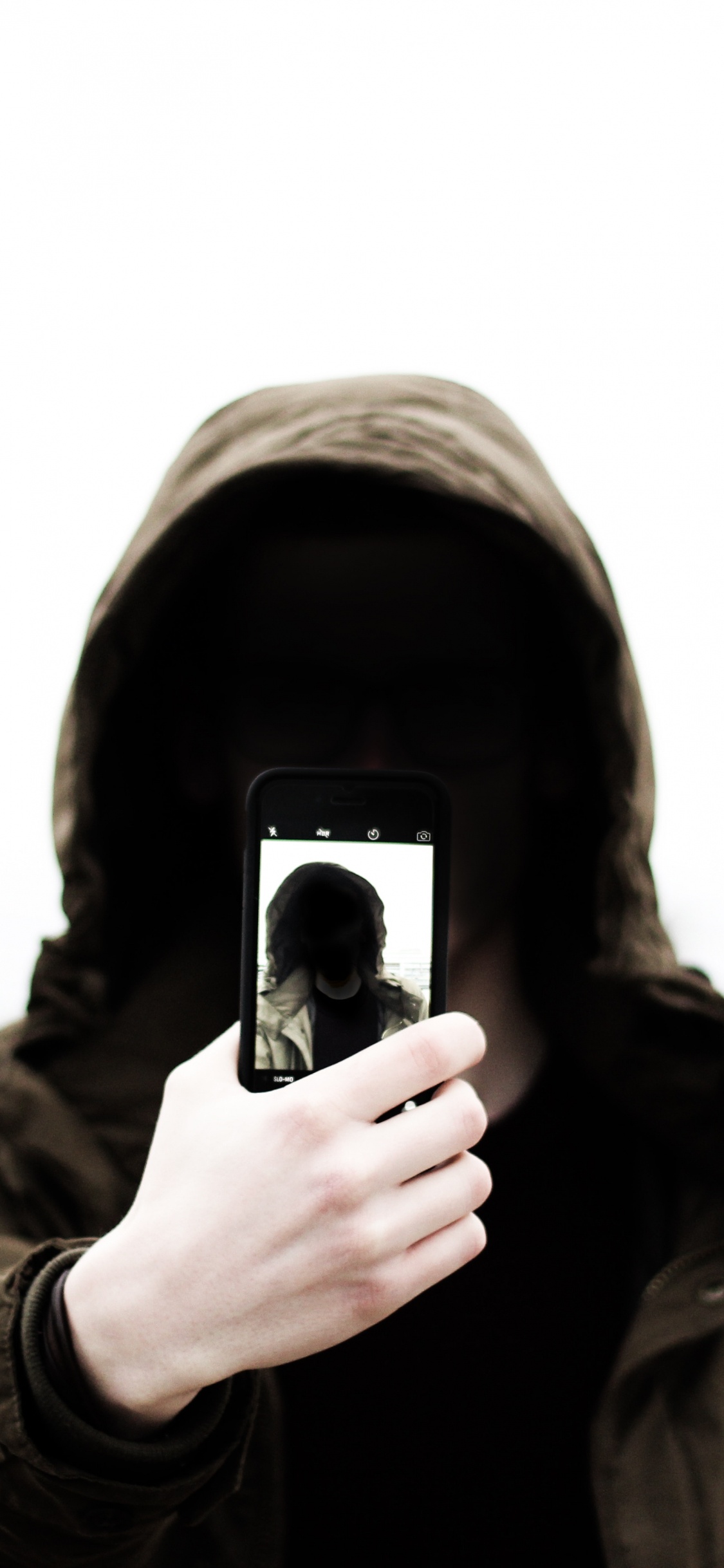 Grayscale Photo of Man in Hoodie Holding Phone. Wallpaper in 1125x2436 Resolution