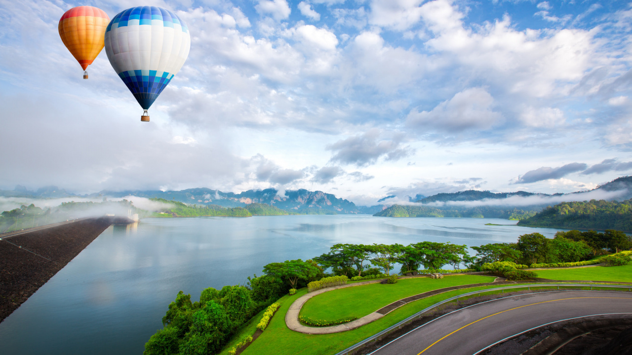 Hot Air Balloon Flying Over Green Grass Field Near Lake During Daytime. Wallpaper in 1280x720 Resolution