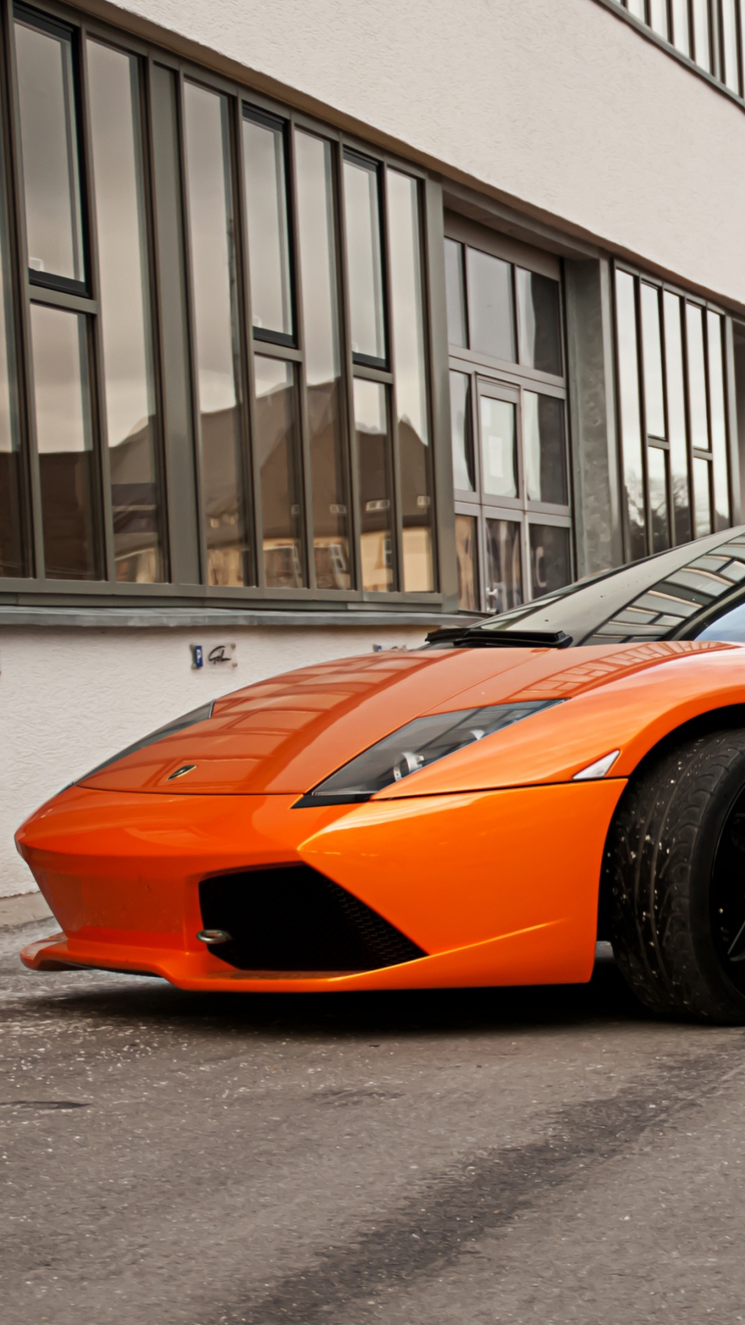 Coupé Orange Garé Sur la Route Près du Bâtiment. Wallpaper in 1080x1920 Resolution