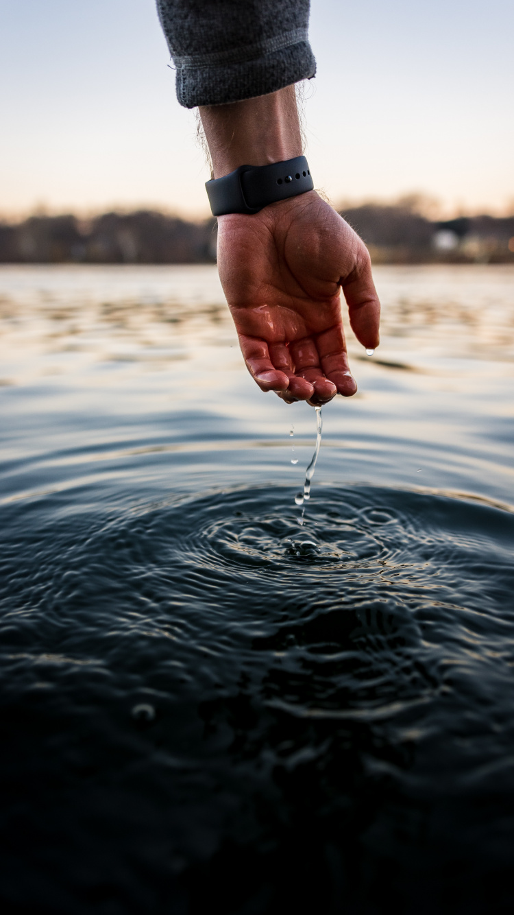 Person, Die Tagsüber Einen Wasserschlauch Auf Dem Wasser Hält. Wallpaper in 750x1334 Resolution