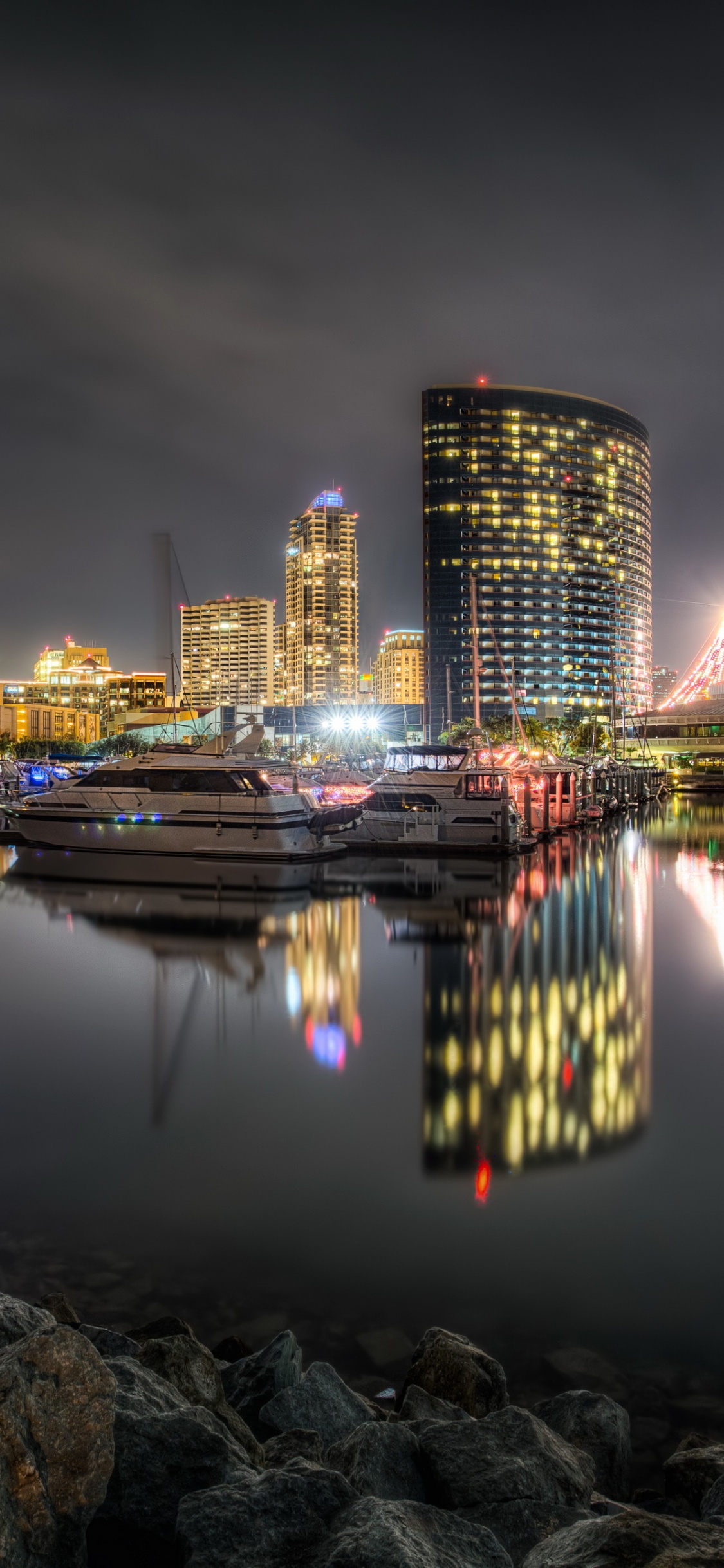 City Skyline Across Body of Water During Night Time. Wallpaper in 1125x2436 Resolution