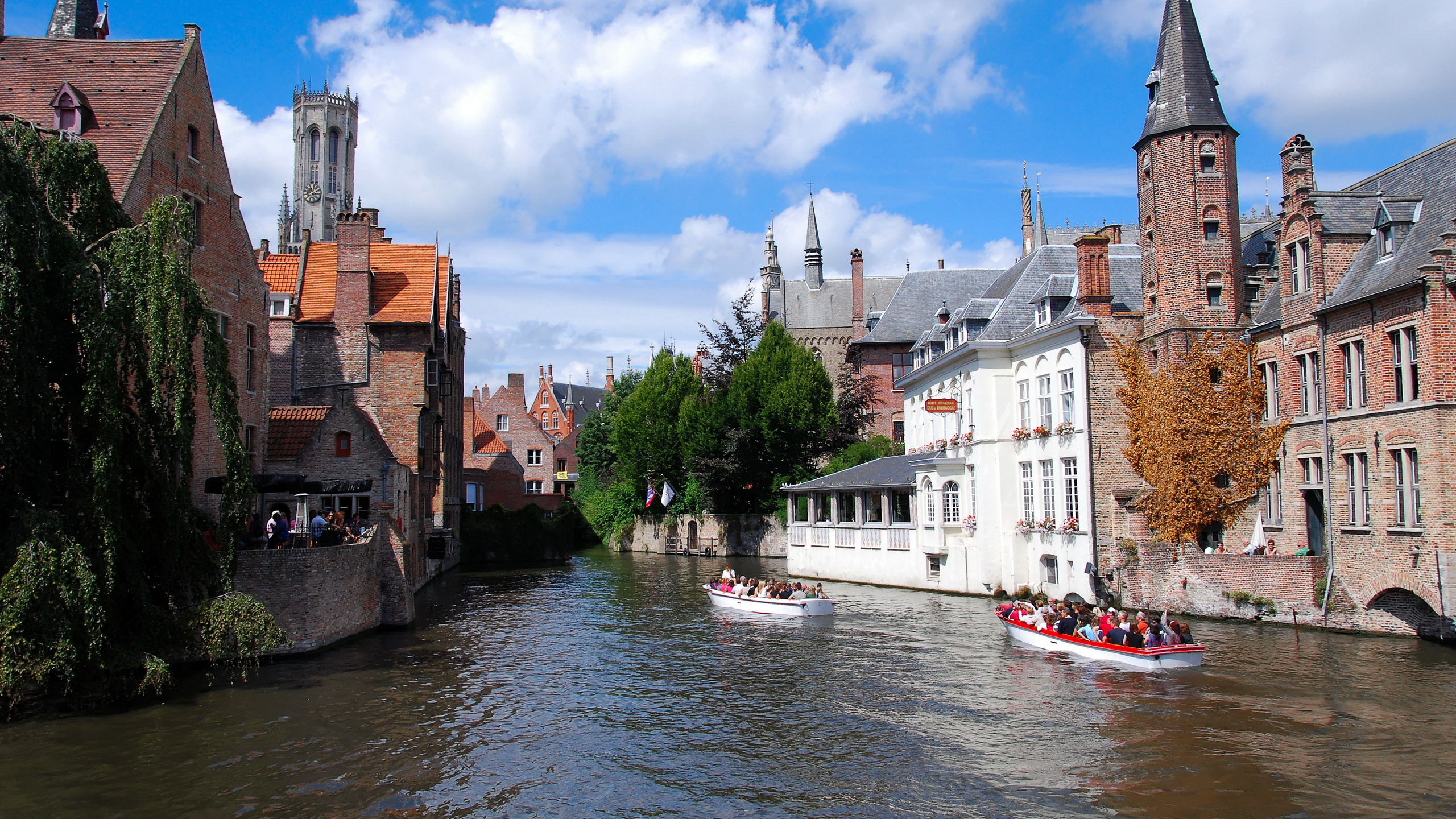 White Boat on River Near Brown Concrete Building Under Blue Sky During Daytime. Wallpaper in 2560x1440 Resolution