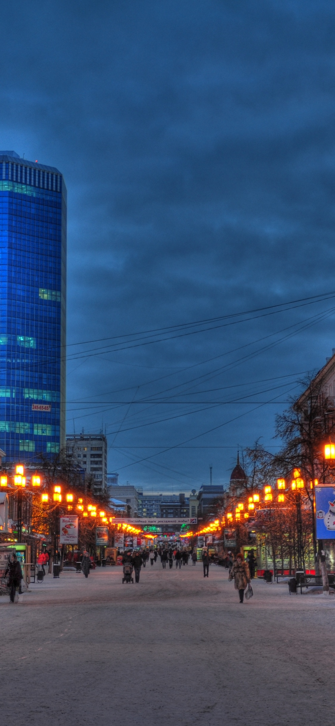 People Walking on Sidewalk Near High Rise Buildings During Night Time. Wallpaper in 1125x2436 Resolution