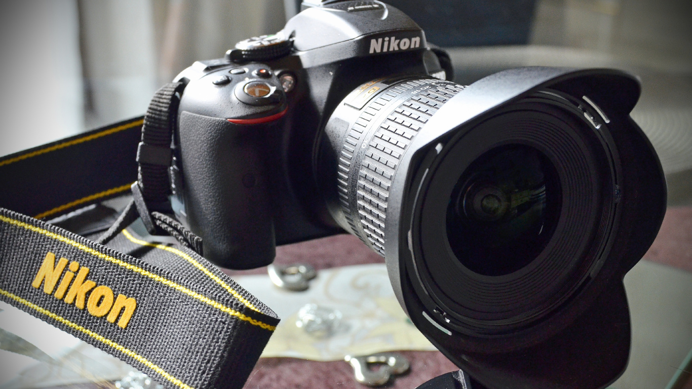 Schwarze Nikon Dslr Kamera Auf Braunem Und Schwarzem Textil. Wallpaper in 1366x768 Resolution