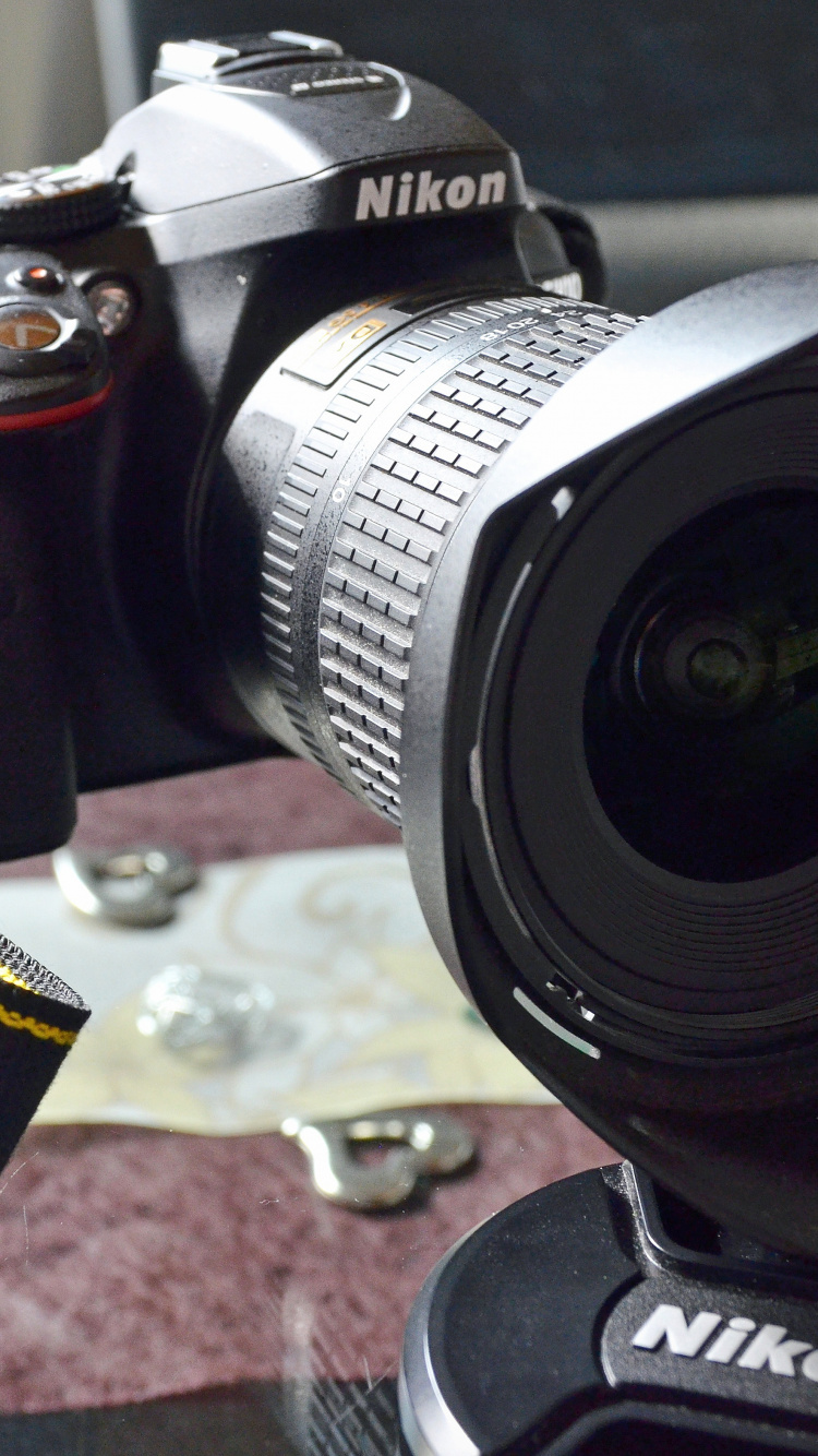 Schwarze Nikon Dslr Kamera Auf Braunem Und Schwarzem Textil. Wallpaper in 750x1334 Resolution
