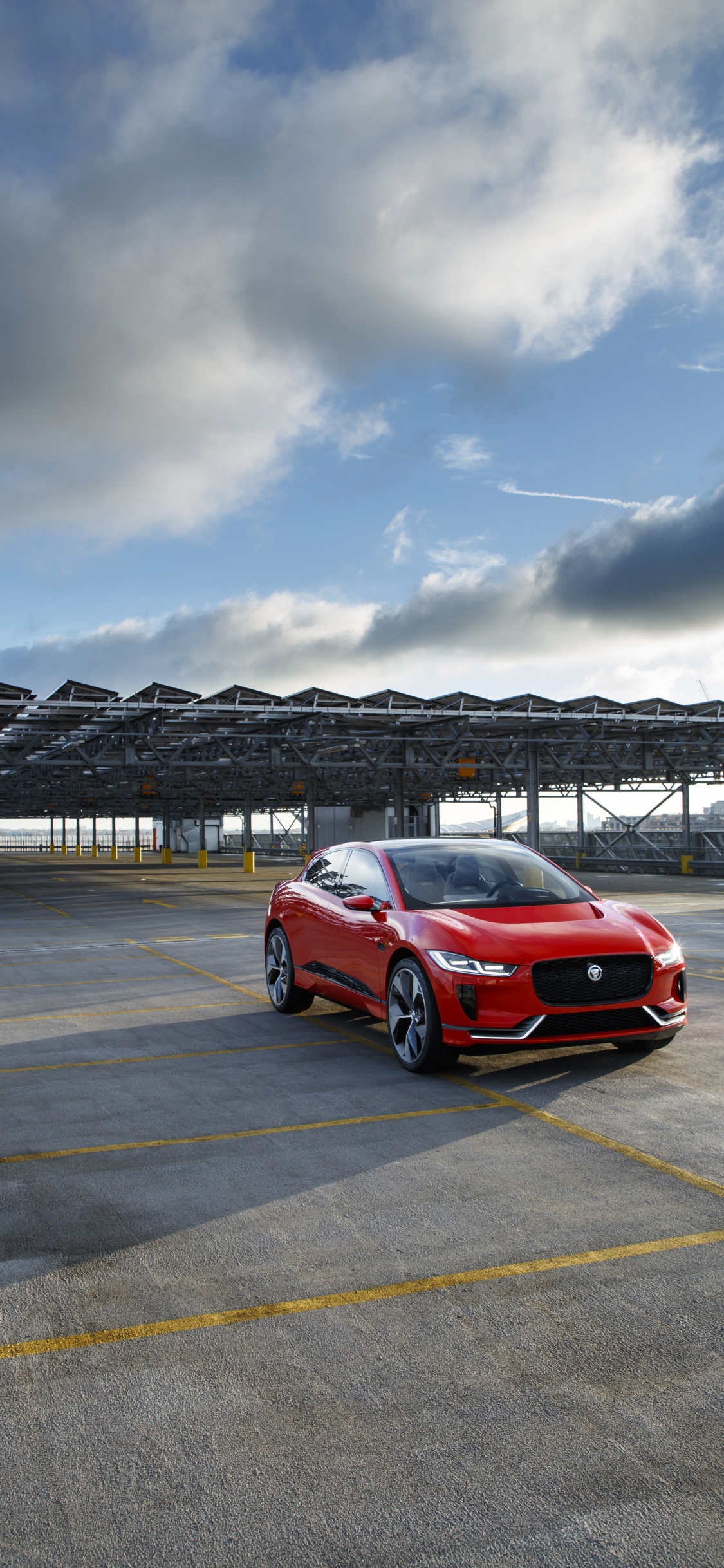 Red Car on Gray Asphalt Road Under Gray Cloudy Sky During Daytime. Wallpaper in 1125x2436 Resolution