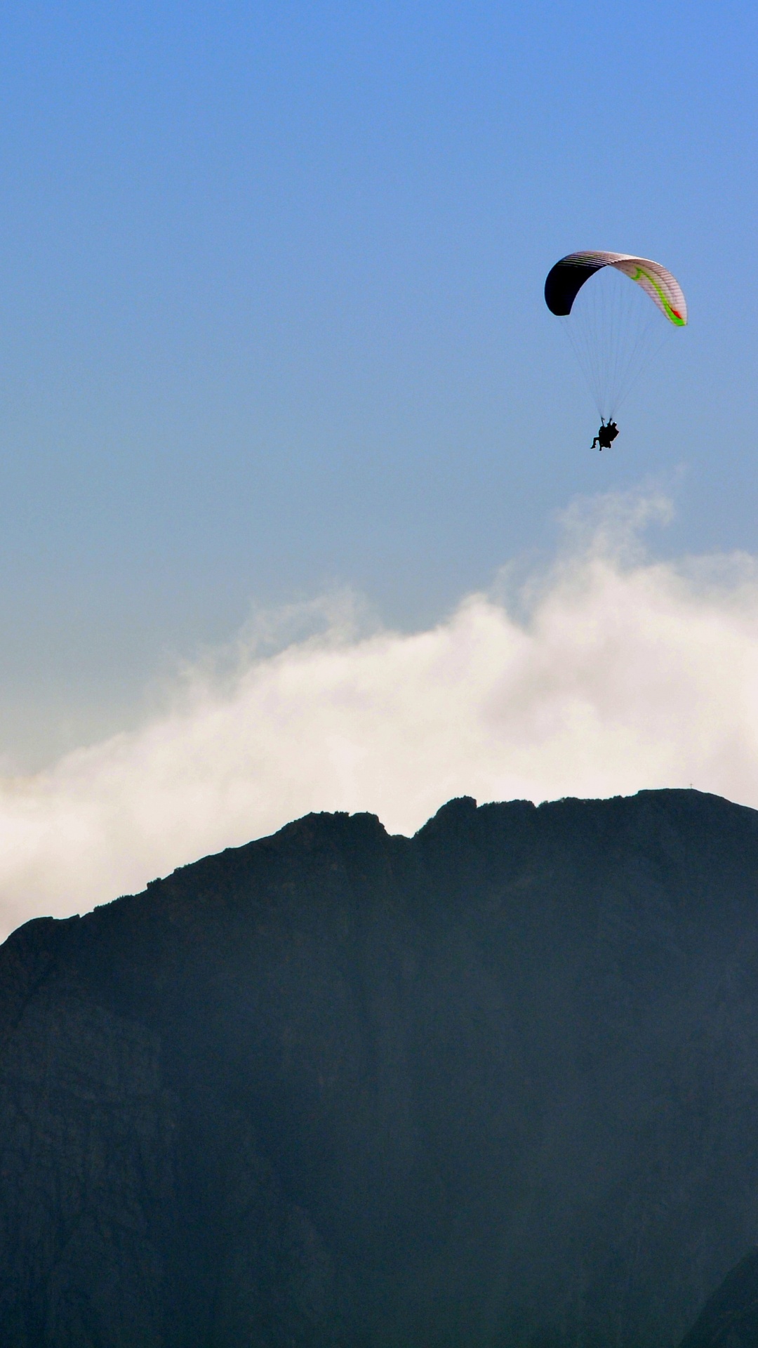 Person Riding Parachute Over Mountain. Wallpaper in 1080x1920 Resolution