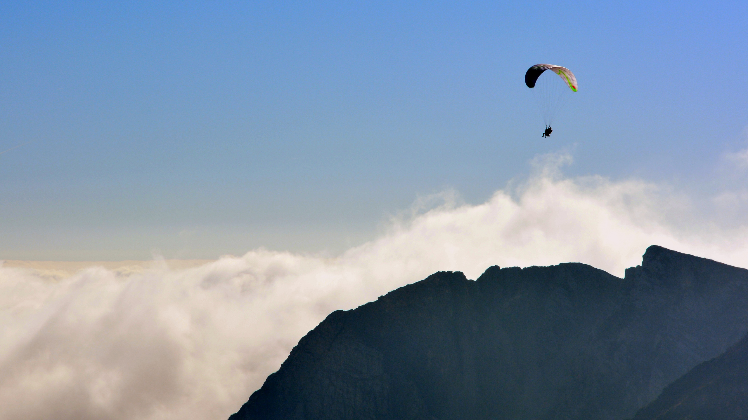 Person Riding Parachute Over Mountain. Wallpaper in 2560x1440 Resolution