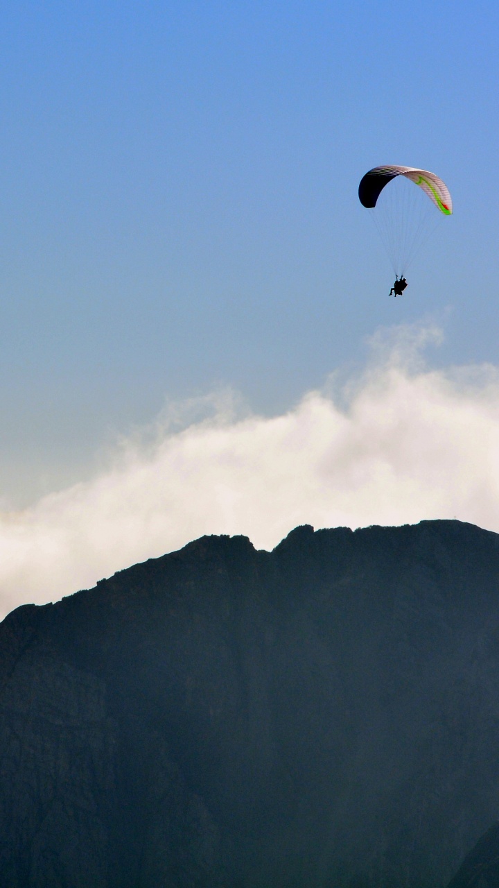 Person Riding Parachute Over Mountain. Wallpaper in 720x1280 Resolution