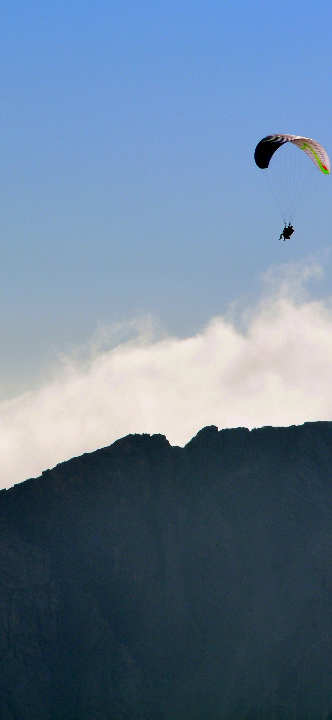 Persona Montando en Paracaídas Sobre la Montaña. Wallpaper in 1125x2436 Resolution