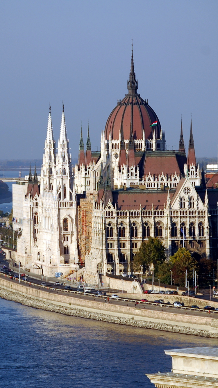 Weißes Und Braunes Betongebäude in Der Nähe Eines Gewässers Tagsüber. Wallpaper in 750x1334 Resolution