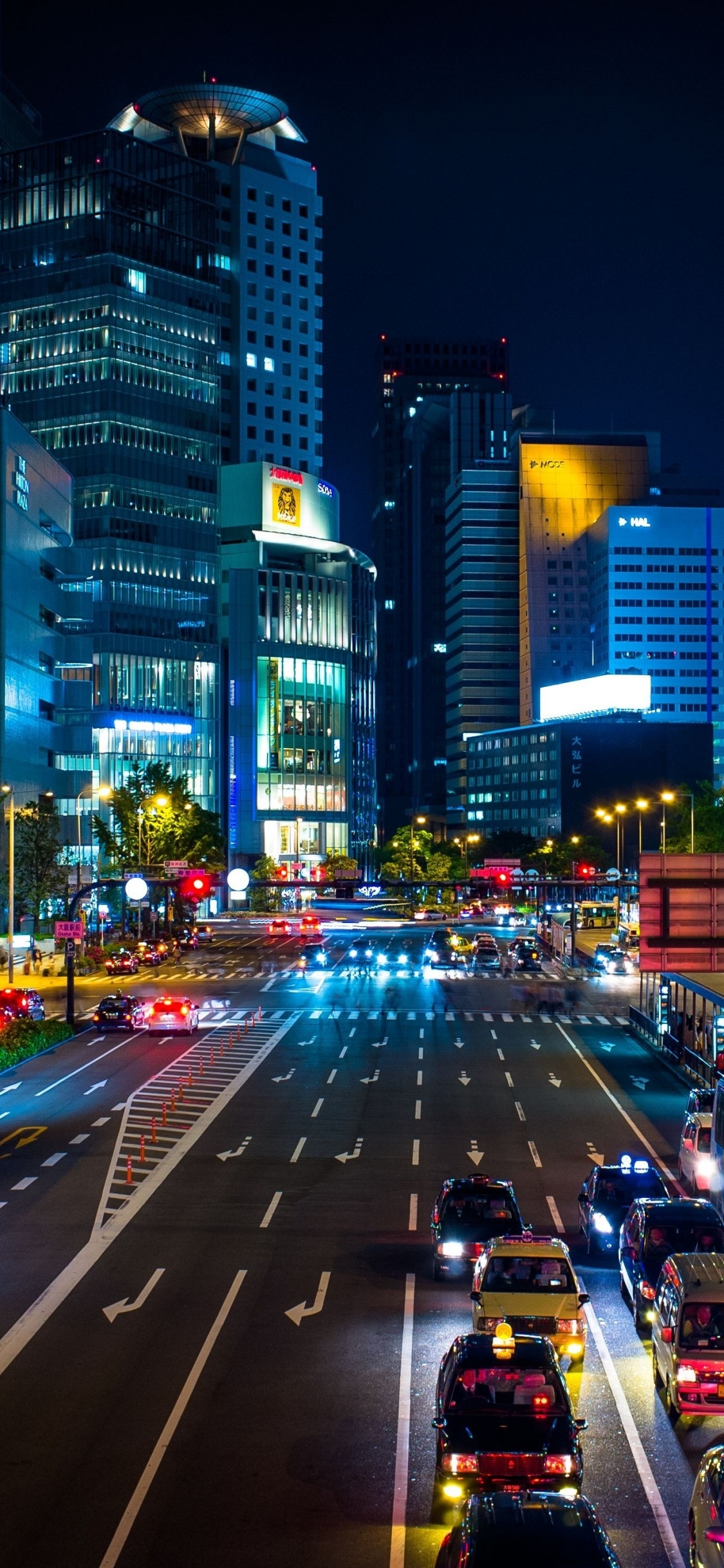 Cars on Road Between High Rise Buildings During Night Time. Wallpaper in 1125x2436 Resolution