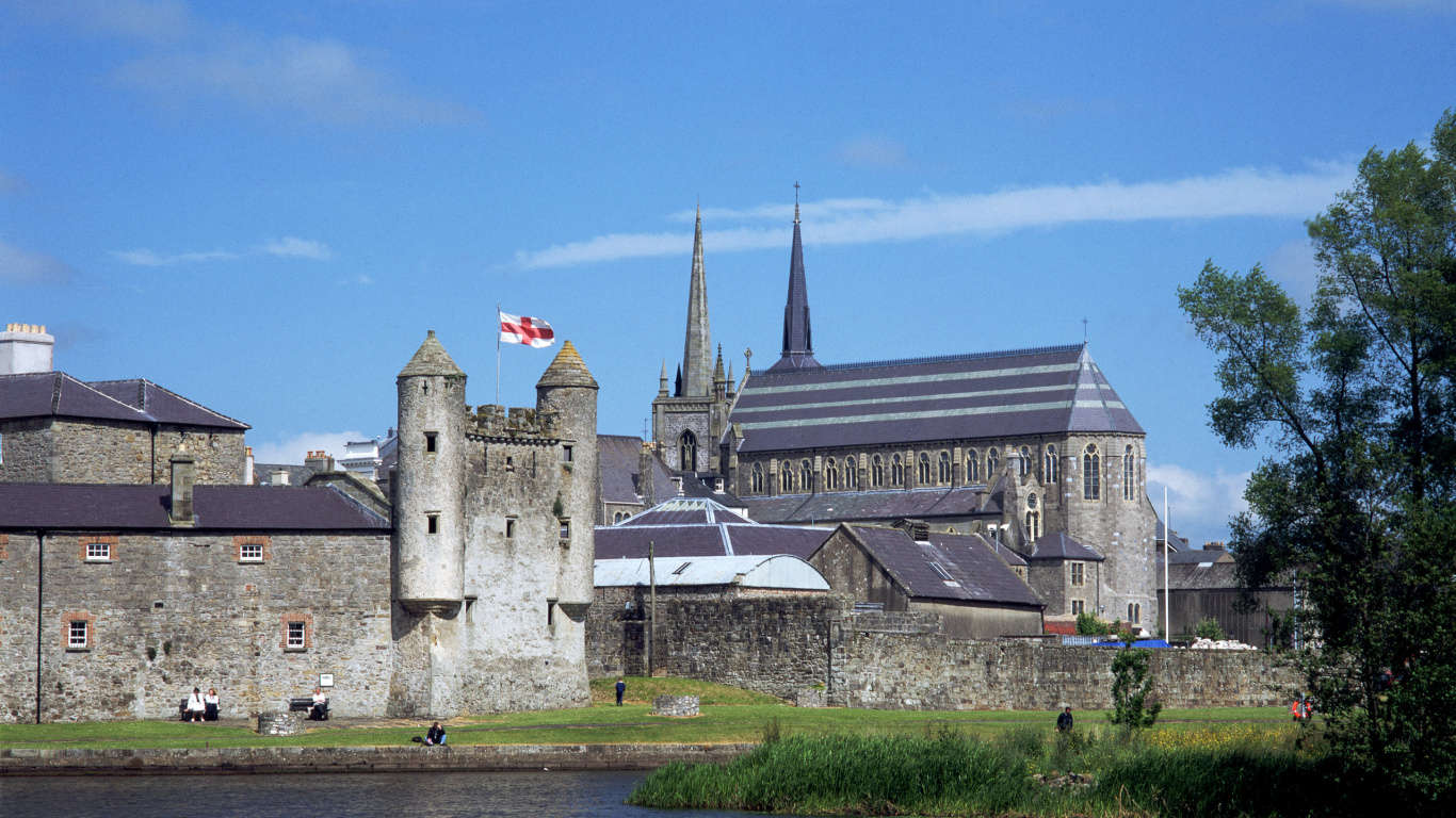 Gray Concrete Building Near River Under Blue Sky During Daytime. Wallpaper in 1366x768 Resolution