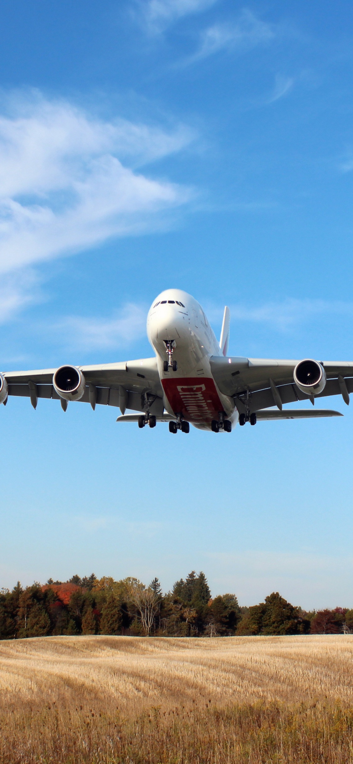 White and Blue Airplane Flying Over Brown Grass Field During Daytime. Wallpaper in 1125x2436 Resolution
