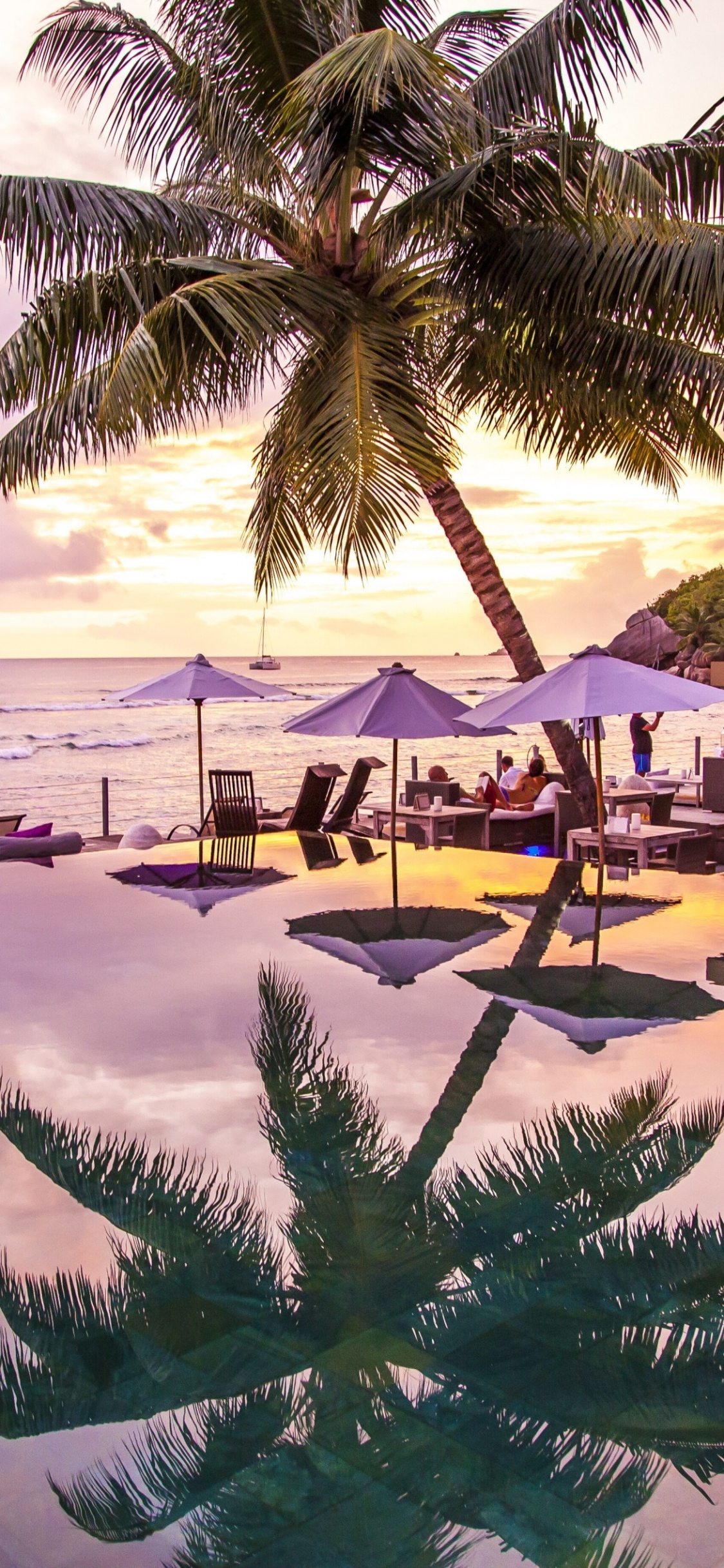 Man in Black Shirt and Gray Pants Walking on Beach During Daytime. Wallpaper in 1125x2436 Resolution