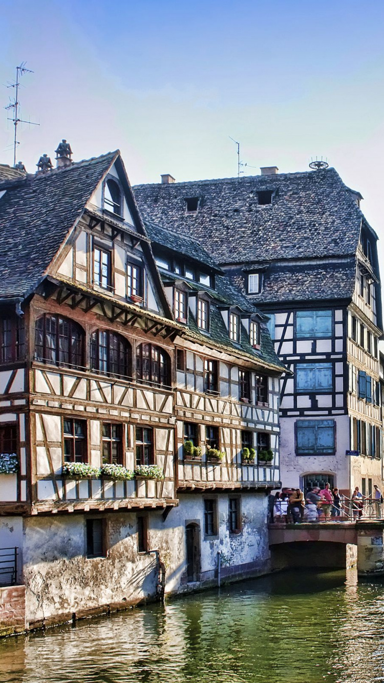 Brown and White Concrete Building Beside River During Daytime. Wallpaper in 750x1334 Resolution