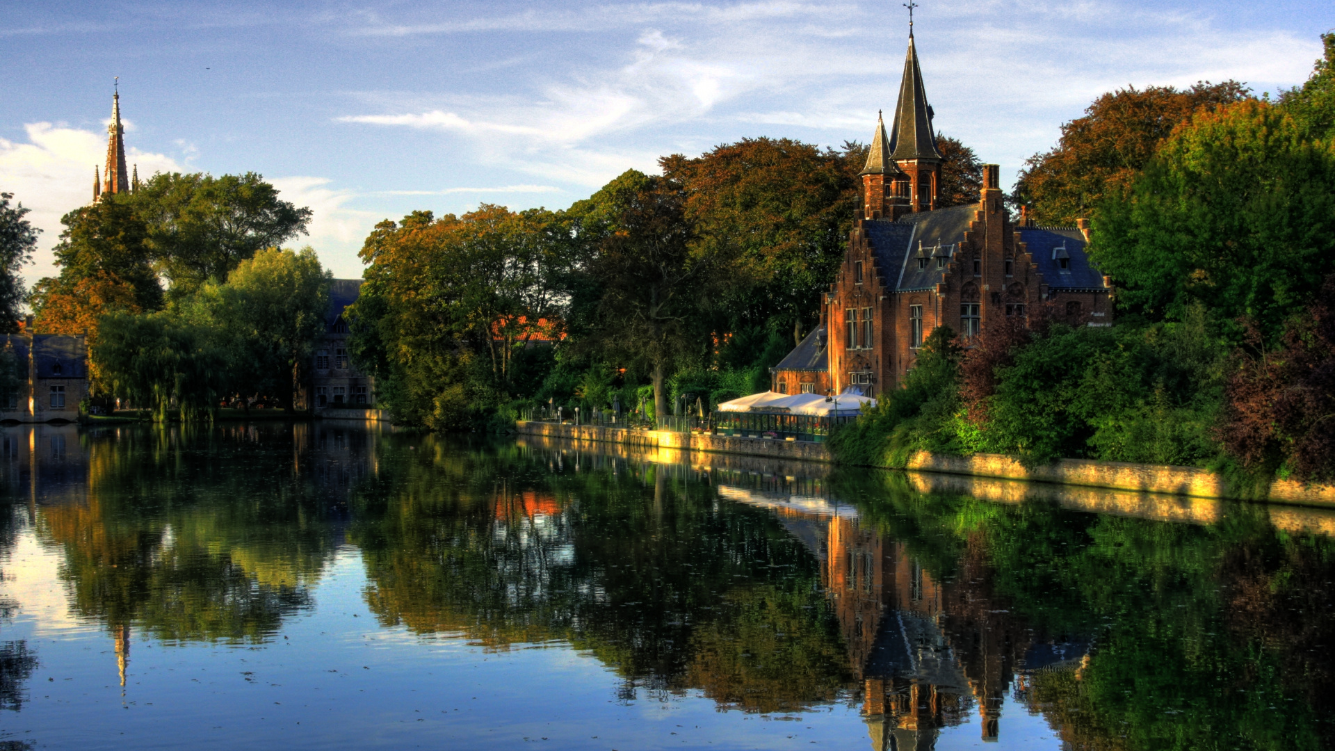 Brown Concrete Building Near Green Trees and Body of Water During Daytime. Wallpaper in 1920x1080 Resolution