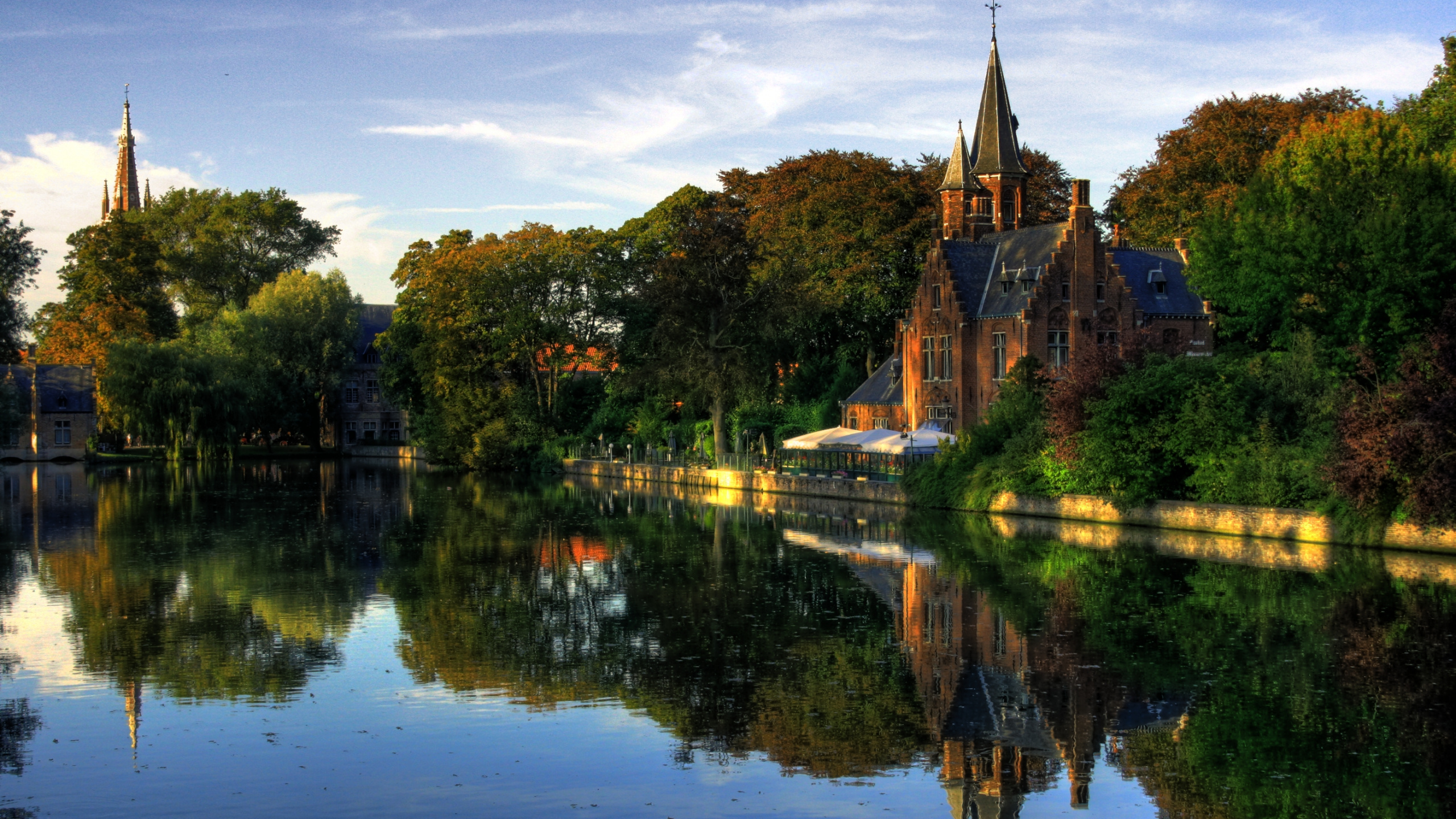 Brown Concrete Building Near Green Trees and Body of Water During Daytime. Wallpaper in 2560x1440 Resolution