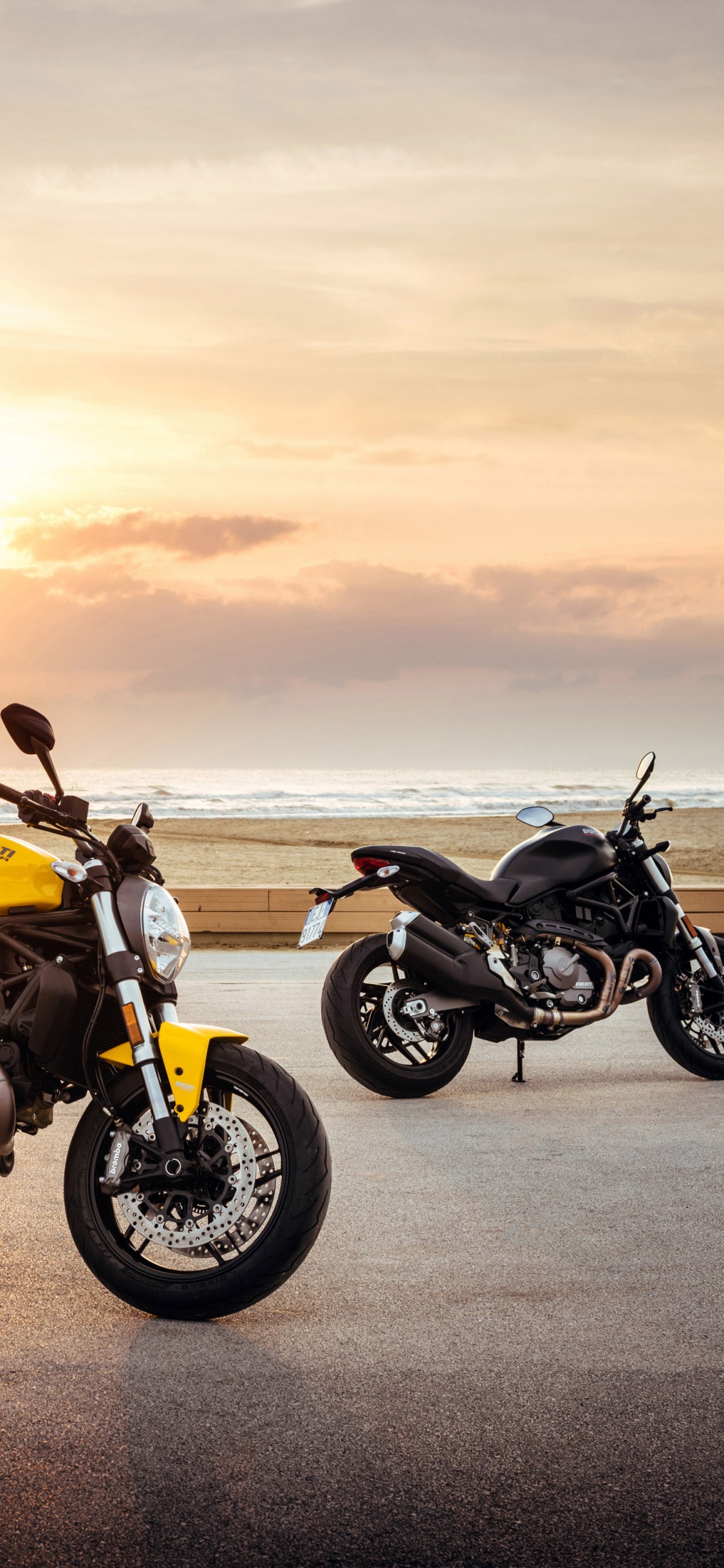 Gelbes Und Schwarzes Cruiser-Motorrad Auf Grauer Asphaltstraße Bei Sonnenuntergang. Wallpaper in 1125x2436 Resolution