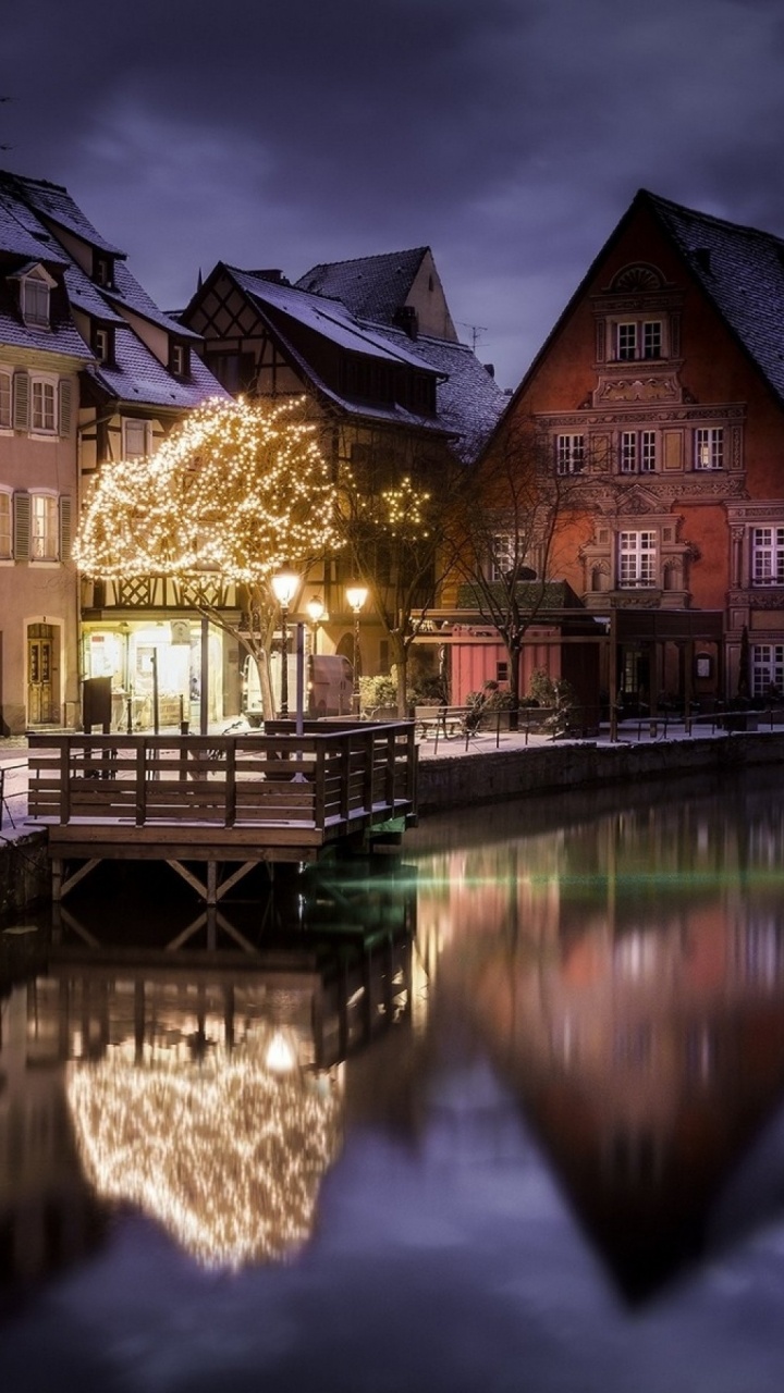 Edificio de Hormigón Marrón y Negro Junto al Río Durante la Noche. Wallpaper in 720x1280 Resolution