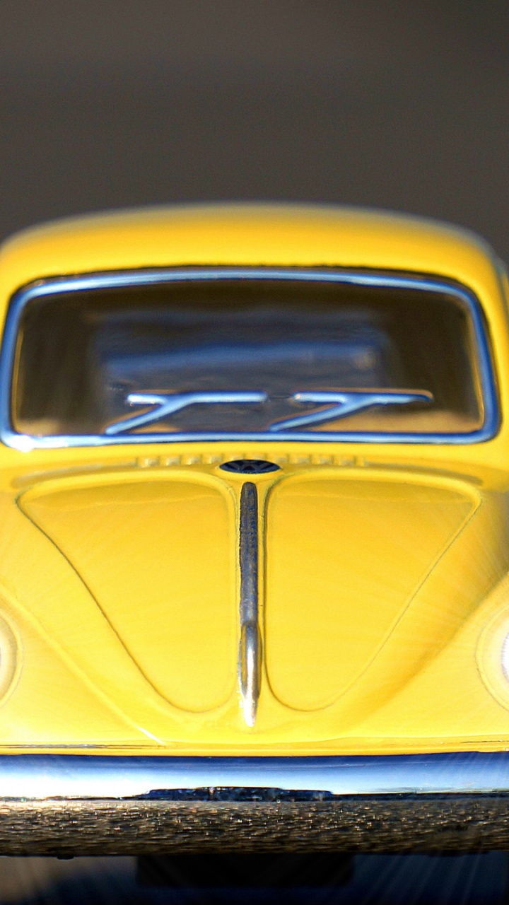 Volkswagen Beetle Amarillo Sobre Superficie de Madera Negra. Wallpaper in 720x1280 Resolution