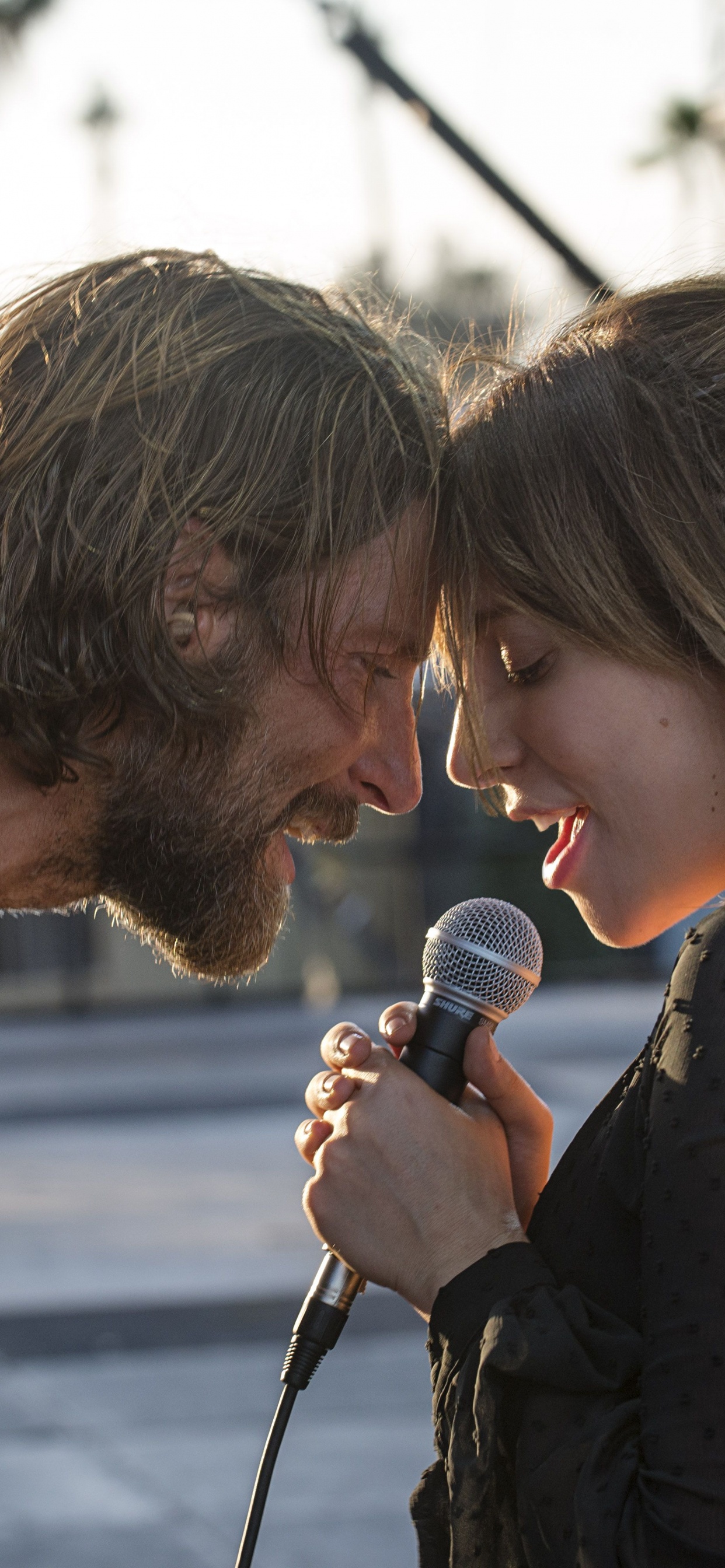 Mann im Schwarzen T-Shirt Mit Rundhalsausschnitt, Der Mikrofon Neben Frau in Schwarz-weißem Polka Hält. Wallpaper in 1242x2688 Resolution