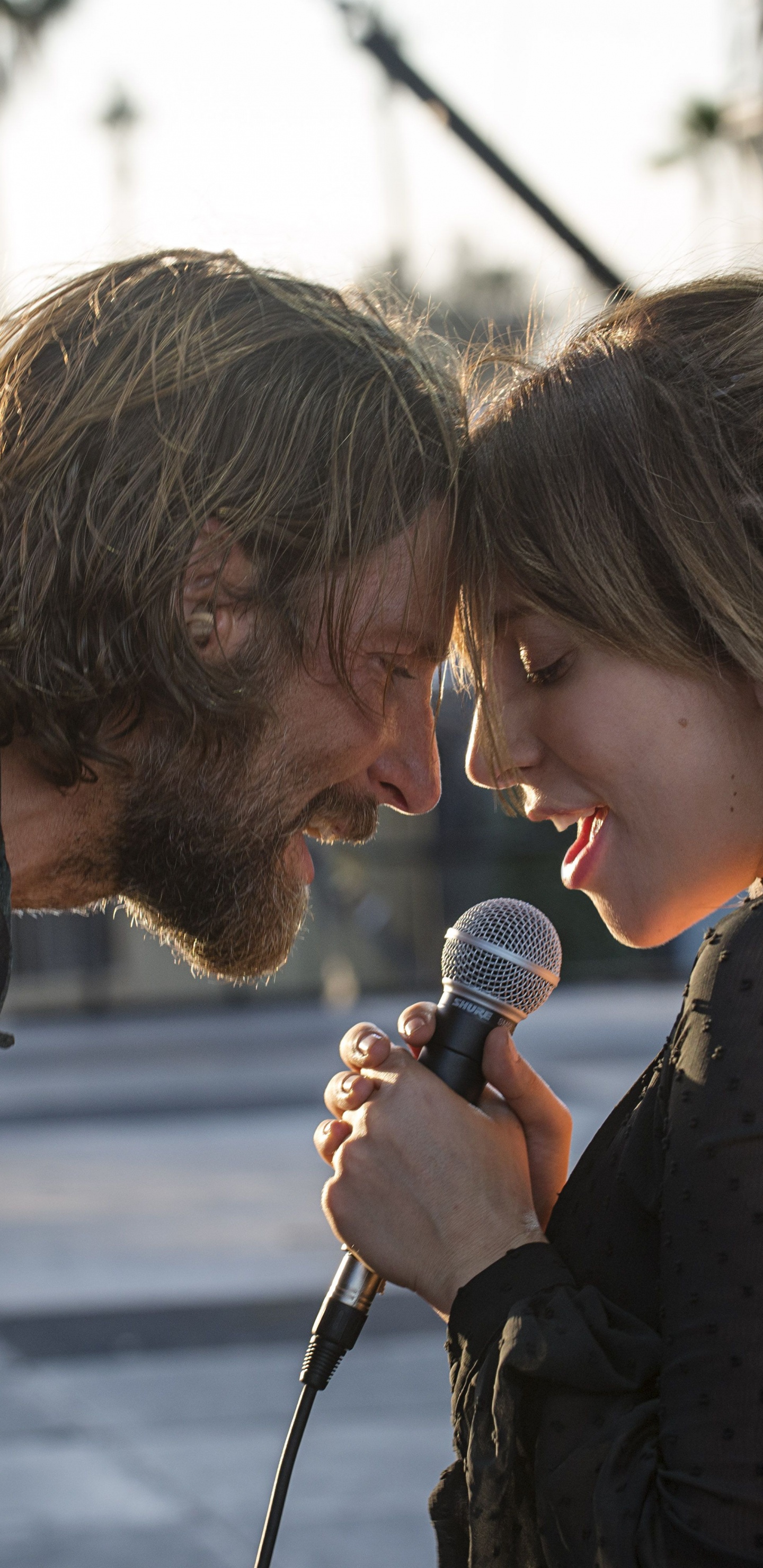 Hombre en Camiseta Negra Con Cuello Redondo Sosteniendo Micrófono Junto a Una Mujer en Polka Blanco y Negro. Wallpaper in 1440x2960 Resolution