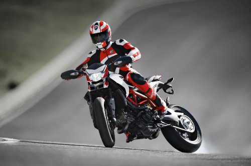 Image man in red and black motorcycle suit riding on red and black sports bike