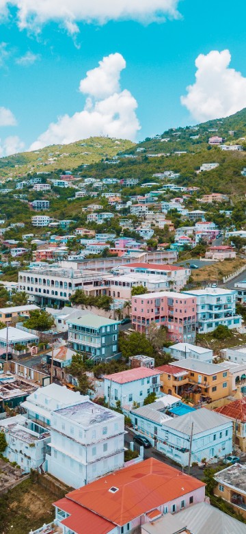 Image aerial view of city buildings on green mountain during daytime