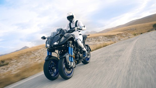 Image man in black and gray motorcycle suit riding on black motorcycle on gray asphalt road during