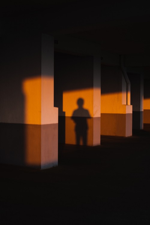 Image silhouette of person standing in front of brown concrete wall