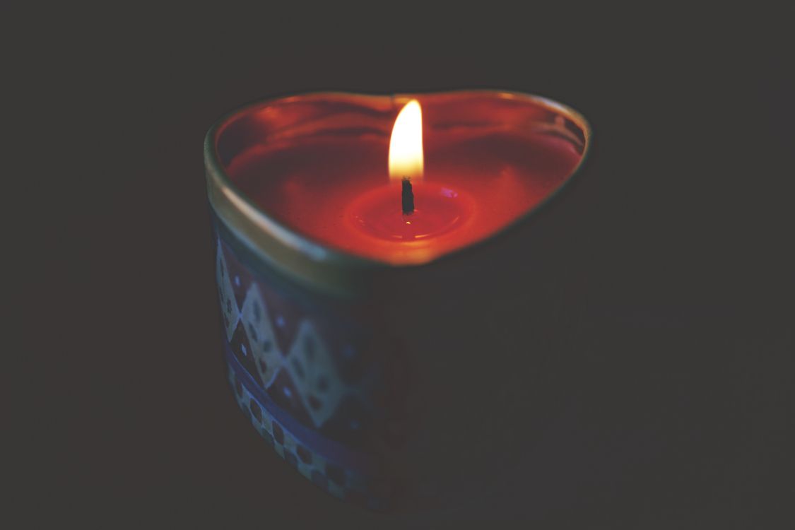 red lighted candle on blue round container