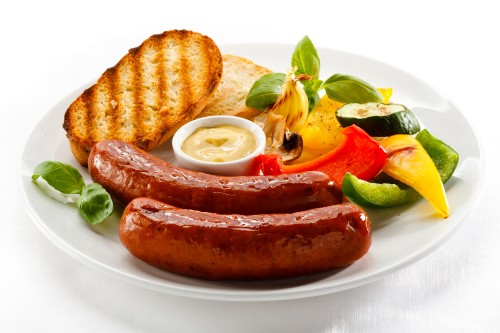 Image sausage with sliced tomato and cucumber on white ceramic plate