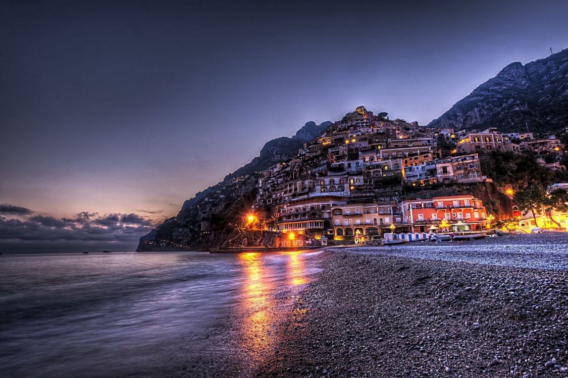 city buildings near body of water during night time