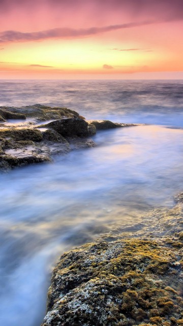 Image rocky shore with water waves during sunset