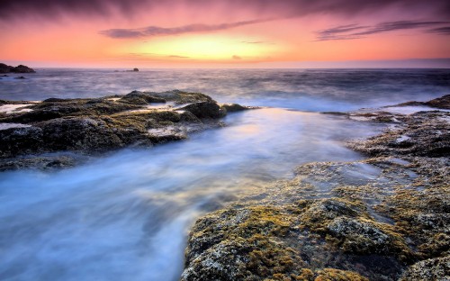 Image rocky shore with water waves during sunset