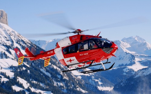 Image red and white helicopter on snow covered ground during daytime