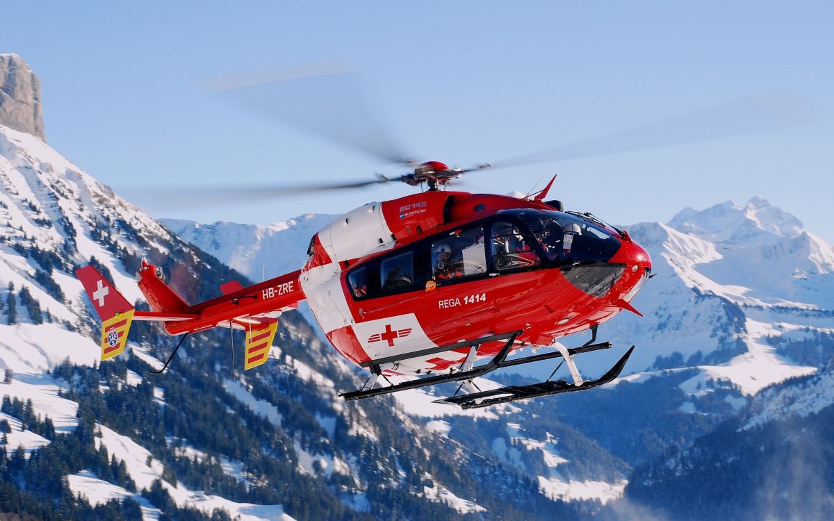 red and white helicopter on snow covered ground during daytime