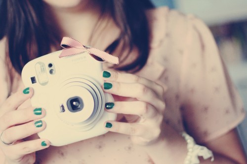 Image woman holding white point and shoot camera