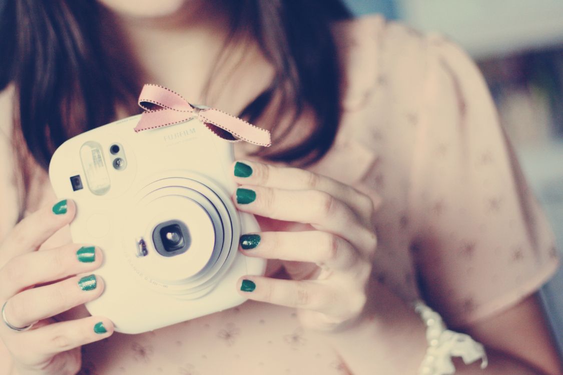 woman holding white point and shoot camera